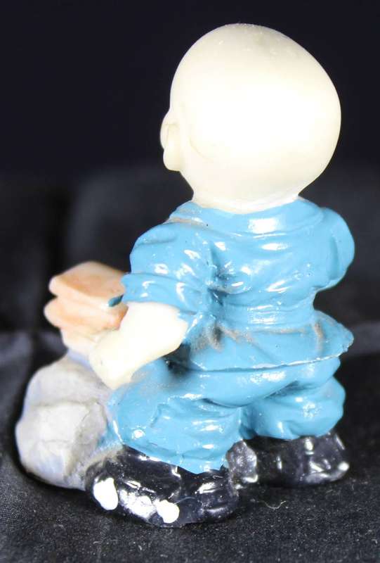 Little monk sitting with book