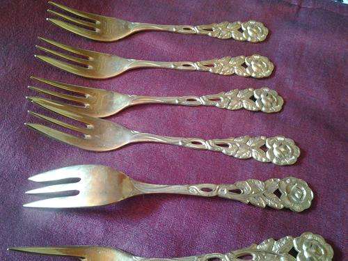 A set of raised rose cake forks in a type of gold plating - lots of filigree raised detailling.