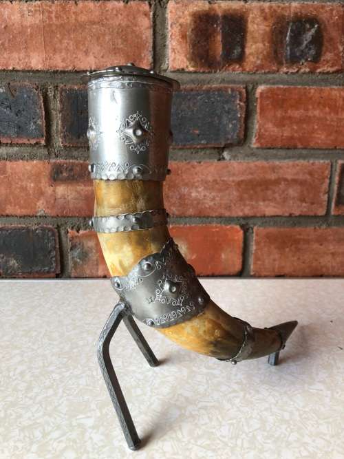A pewter mounted powder horn with removable top, with engravings and embossed decoration