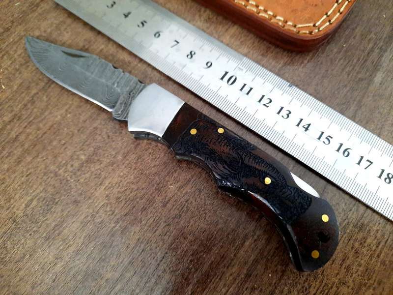 Handmade Damascus steel folding knife with wooden handle scales. Picture engraved. NEW STOCK !