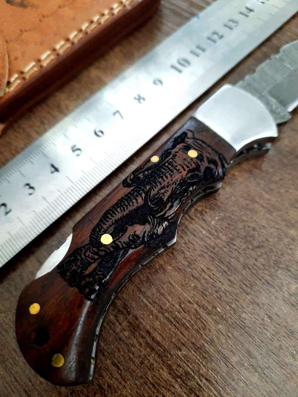 Handmade Damascus steel folding knife with wooden handle scales. Picture engraved. NEW STOCK !