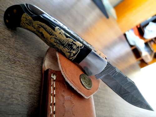 Handmade Damascus steel folding knife with Bull Horn Handle. Art engraved.