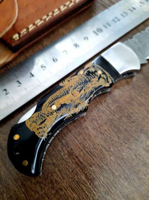 Handmade Damascus steel folding knife with Bull Horn Handle. Art engraved.