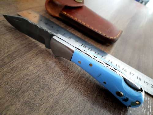 Handmade Damascus steel folding knife with Epoxy Resin handle scales. Leather pouch included.