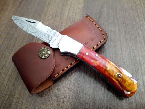 Handmade Damascus steel folding knife with Epoxy Resin handle scales. Leather pouch included.