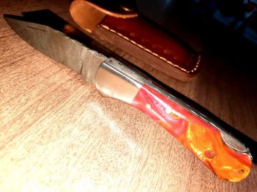 Handmade Damascus steel folding knife with Epoxy Resin handle scales. Leather pouch included.
