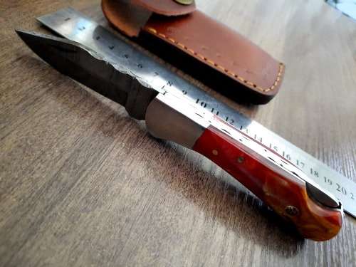 Handmade Damascus steel folding knife with Epoxy Resin handle scales. Leather pouch included.