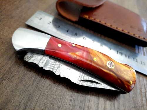 Handmade Damascus steel folding knife with Epoxy Resin handle scales. Leather pouch included.