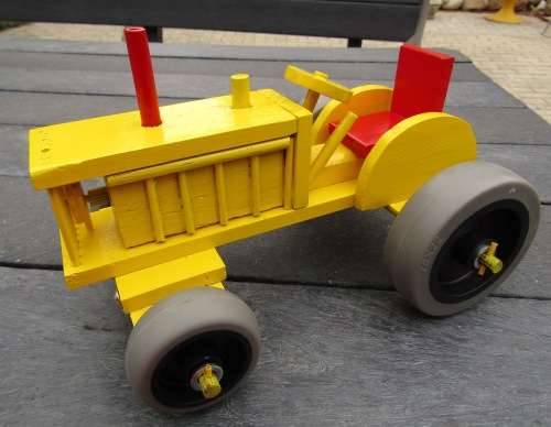 LARGE HAND MADE WOODEN TRACTOR IN BRIGHT YELLOW. VERY STURDY. RUBBER WHEELS. NOT DINKY.