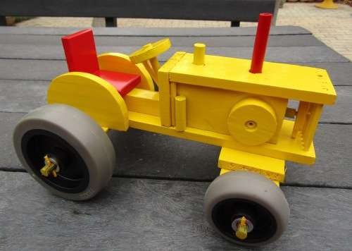 LARGE HAND MADE WOODEN TRACTOR IN BRIGHT YELLOW. VERY STURDY. RUBBER WHEELS. NOT DINKY.