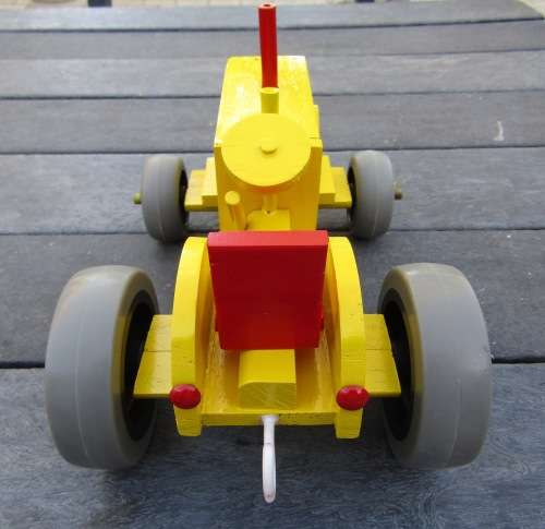 LARGE HAND MADE WOODEN TRACTOR IN BRIGHT YELLOW. VERY STURDY. RUBBER WHEELS. NOT DINKY.