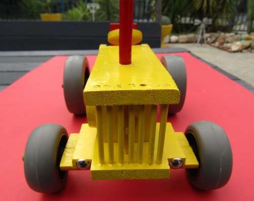 LARGE HAND MADE WOODEN TRACTOR IN BRIGHT YELLOW. VERY STURDY. RUBBER WHEELS. NOT DINKY.