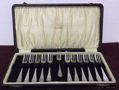 Silver plated set of 11 cake forks, with 1 pickle fork, in original box.