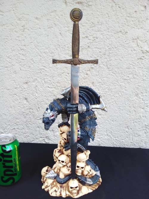 A STUNNING RESIN STATUE OF A DRAGON STANDING ON SKULLS HOLDING A BRASS & STAINLESS SWORD