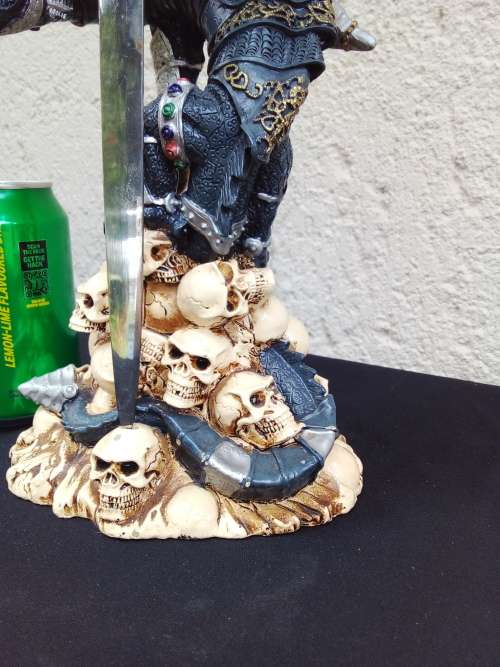 A STUNNING RESIN STATUE OF A DRAGON STANDING ON SKULLS HOLDING A BRASS & STAINLESS SWORD