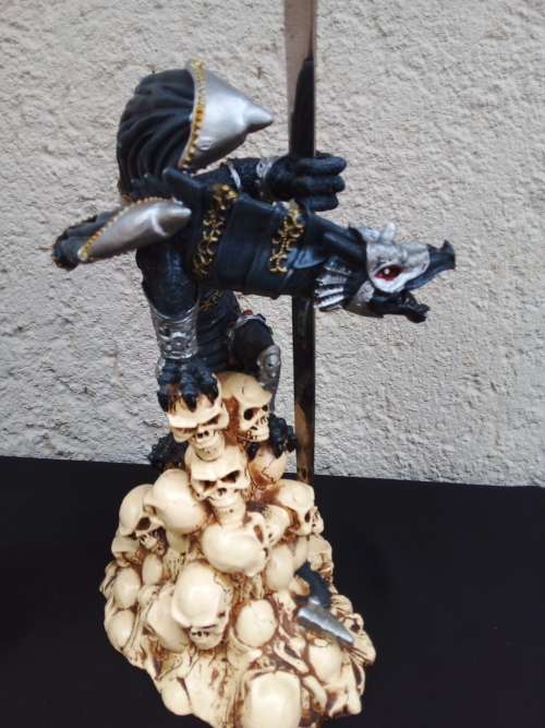 A STUNNING RESIN STATUE OF A DRAGON STANDING ON SKULLS HOLDING A BRASS & STAINLESS SWORD
