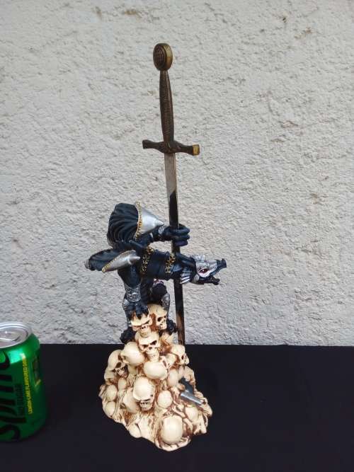 A STUNNING RESIN STATUE OF A DRAGON STANDING ON SKULLS HOLDING A BRASS & STAINLESS SWORD