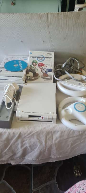 NINTENDO WII CONSOLE INCL.T STEERING AND REMOTES, 2 NUNCHUK ADAPTER, 8 GAME DISCS AND ALL CABLES AS