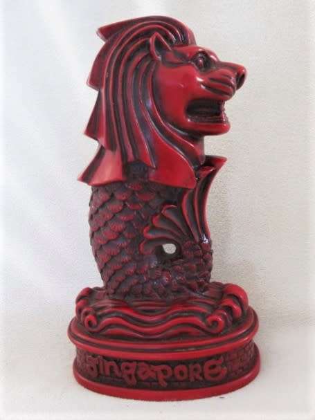 A SOLID RED RESIN PAPERWEIGHT FIGURINE OF SINGAPORE'S MYTHICAL MERLION