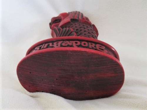 A SOLID RED RESIN PAPERWEIGHT FIGURINE OF SINGAPORE'S MYTHICAL MERLION
