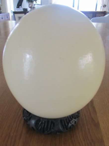 AN OSTRICH EGG ON CARVED WOODEN STAND DEPICTING TWO ZEBRAS DRINKING WATER