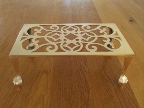 A LARGE ANTIQUE BRASS FIRE HEARTH TRIVET WITH BALL AND CLAW FEET
