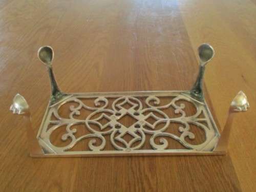 A LARGE ANTIQUE BRASS FIRE HEARTH TRIVET WITH BALL AND CLAW FEET