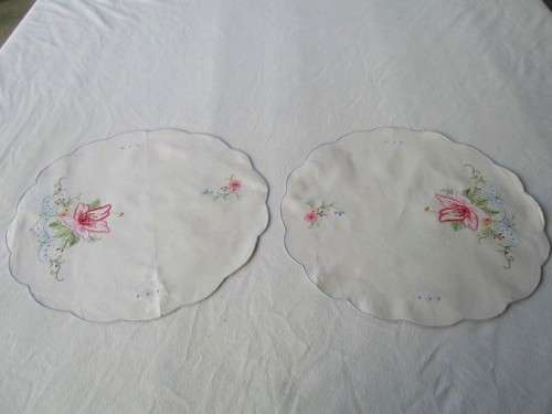A SET OF TWO SMALL, ROUND VINTAGE HAND EMBROIDERED CLOTHS/DOILIES WITH LILY DESIGN