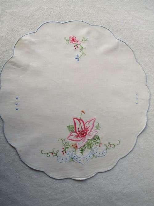 A SET OF TWO SMALL, ROUND VINTAGE HAND EMBROIDERED CLOTHS/DOILIES WITH LILY DESIGN