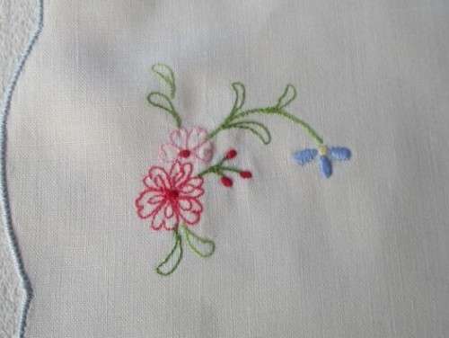 A SET OF TWO SMALL, ROUND VINTAGE HAND EMBROIDERED CLOTHS/DOILIES WITH LILY DESIGN