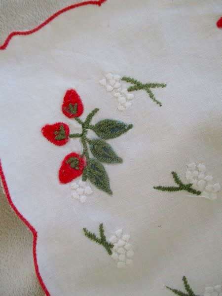 A CHEERFUL EMBROIDERED CLOTH WITH BERRIES AND SCALLOPED BORDER