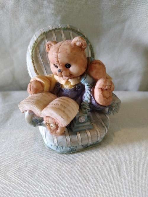 Teddy bear in blue armchair talking on the telephone