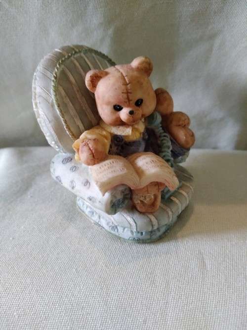Teddy bear in blue armchair talking on the telephone