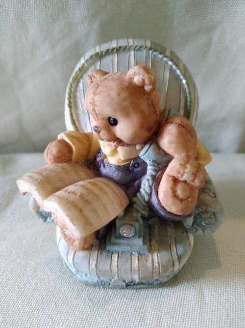 Teddy bear in blue armchair talking on the telephone