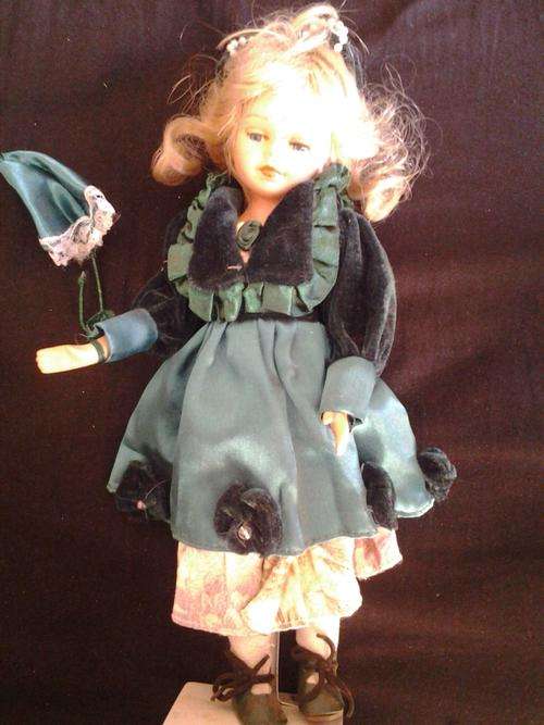 Porcelain doll with green clothes and umbrella