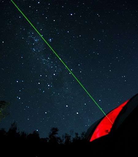 green laser pointer pointing at the sky