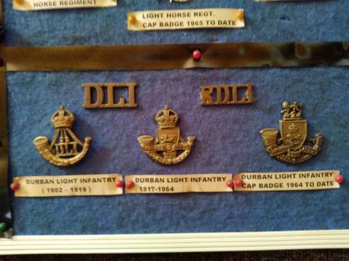 Display of South African Traditional Regiments cap/beret badges, shoulder titles and collar badges.