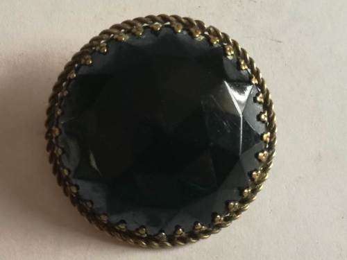 Round decorative black brooch with brass backing