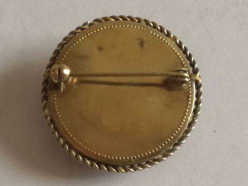 Round decorative black brooch with brass backing