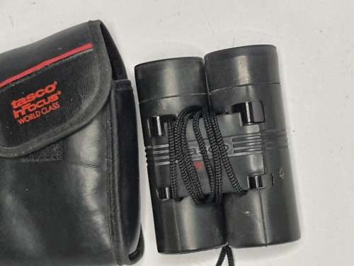 A USED TASCO POCKET BINOCUARS WITH ITS ORIGINAL COVER SOLD AS IS