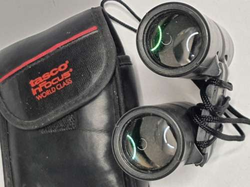 A USED TASCO POCKET BINOCUARS WITH ITS ORIGINAL COVER SOLD AS IS