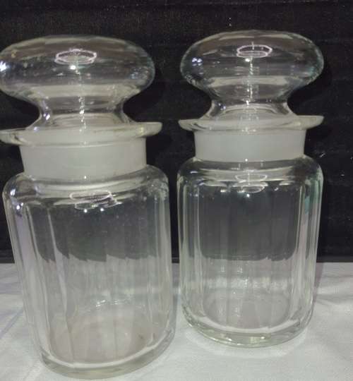 A SET OF 2 STORAGE GLASS BOTTLE CONTAINERS THE ONE LID WAS REPAIRED BEFORE SOLD AS IS
