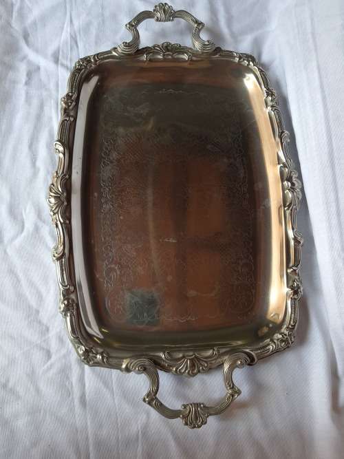 A VINTAGE SILVER PLATED SERVING TRAY WITH ORNATE HANDLES SOLD AS IS