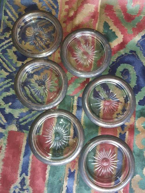 A vintage set of 6 cut glass coasters with silver plated brims sold as is