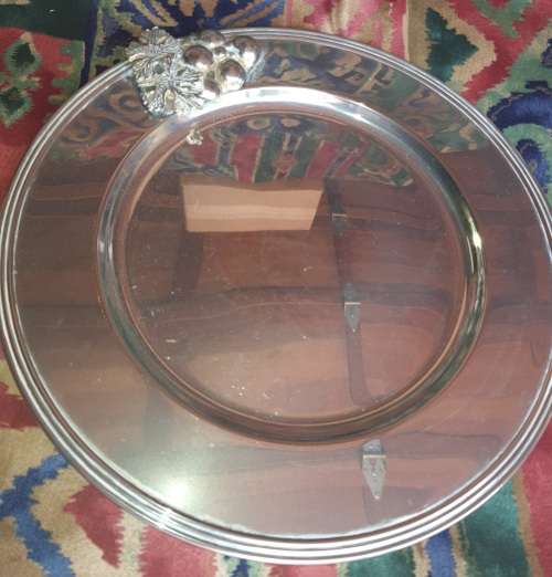 A VINTAGE ROUND  STAINLESS STEEL WITH A GRAPE VINE DESIGN ON IT SOLD AS IS