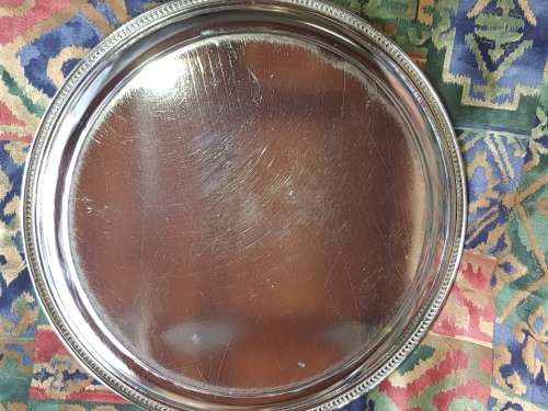 A VINTAGE ROUND SILVER PLATED SERVING TRAY SOLD AS IS