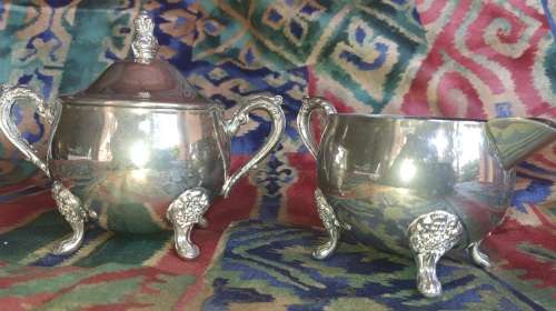A VINTAGE PAIR OF SILVERPLATED UTENSILS , A CREAMER AND A SUGAR BOWL