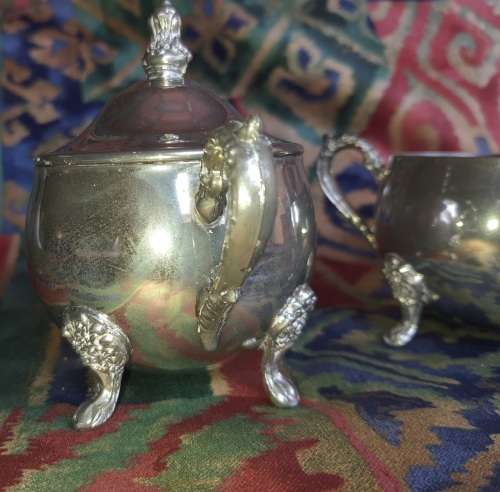 A VINTAGE PAIR OF SILVERPLATED UTENSILS , A CREAMER AND A SUGAR BOWL