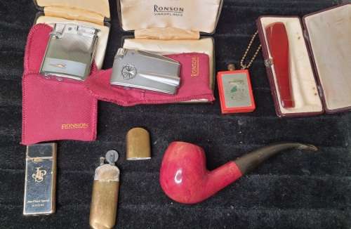 AN ANTIQUE COLLECTION SMOKER COLLECTORS ITEMS RARE LIGHTERS AND A PIPE SOLD AS IS