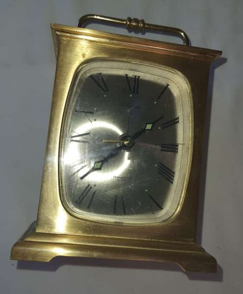 A BRONZE RYTHM TRANSSISTER ALARM CLOCK SOLD AS IS